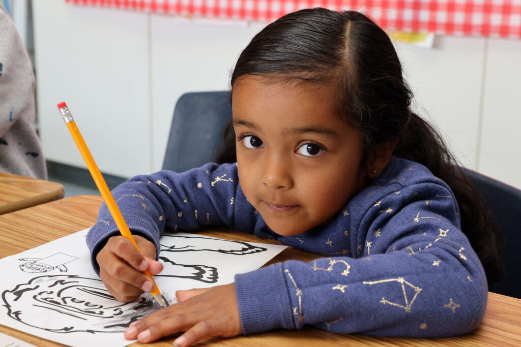 Young girl writing with pencil at her desk