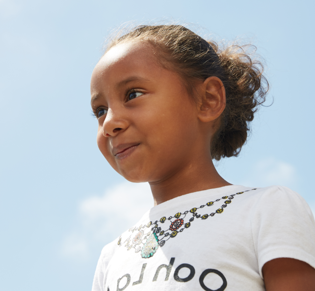 Young girl staring forward with blue sky in background