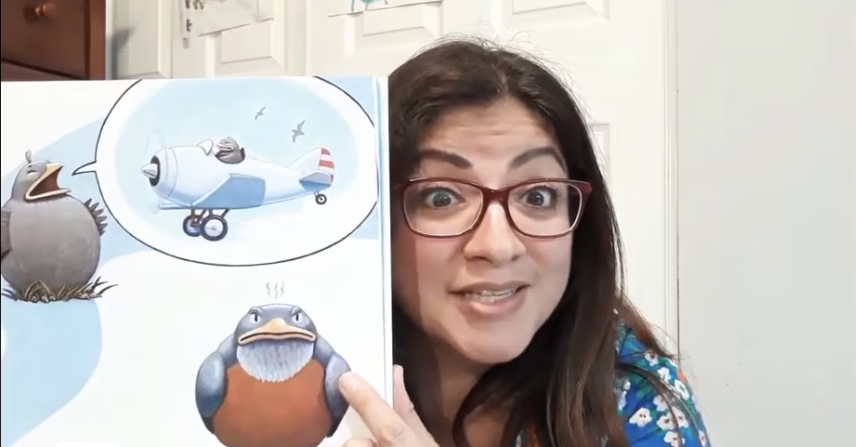 Image of a woman with long brown hair holding up a children's picture book