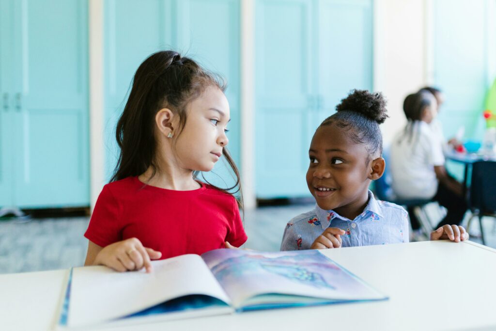 two young girls reading picture book