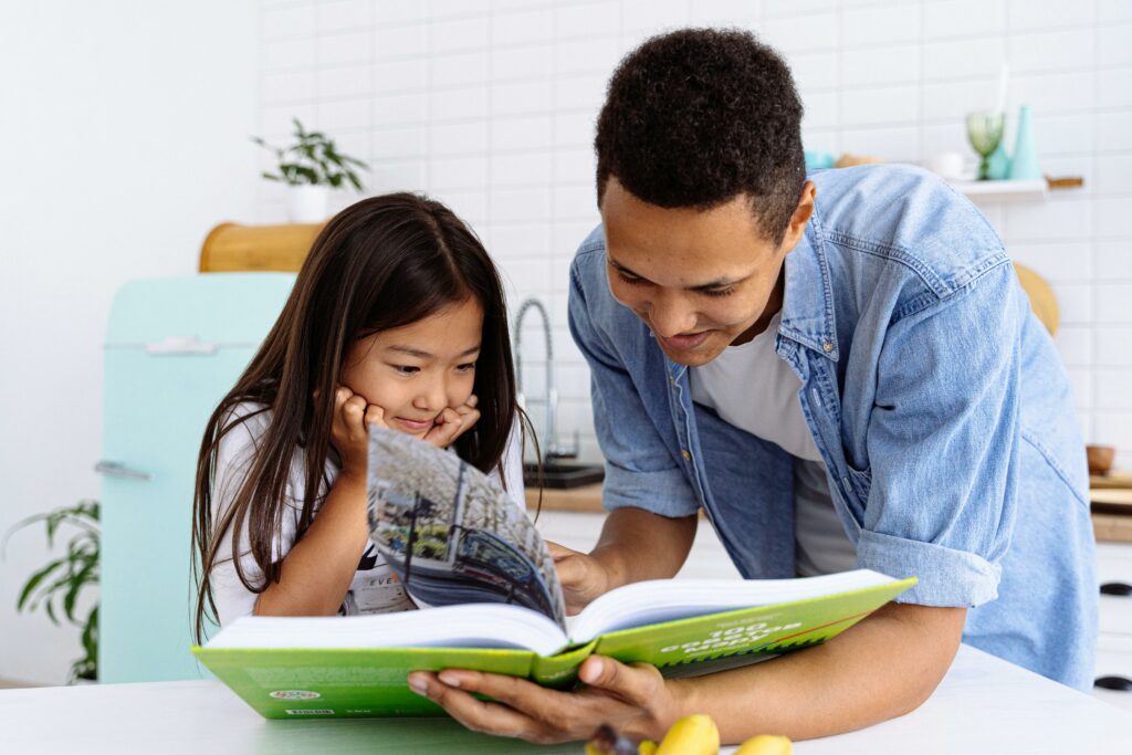 dad reading cookbook with daughter